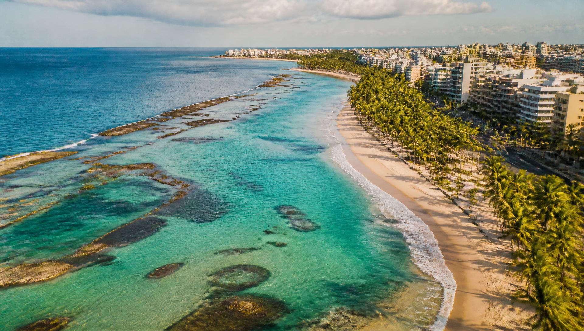 Vista aérea da orla de Maceió com piscinas naturais, praia de areia clara e coqueirais